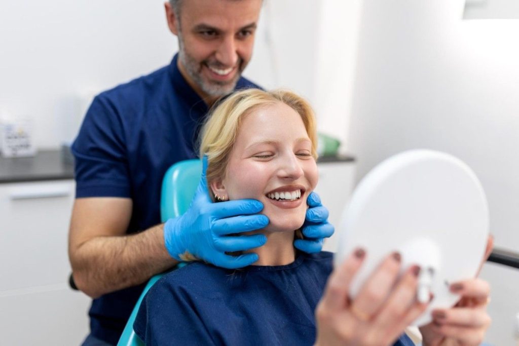 A dentist and girl is smiling after teeth work done 